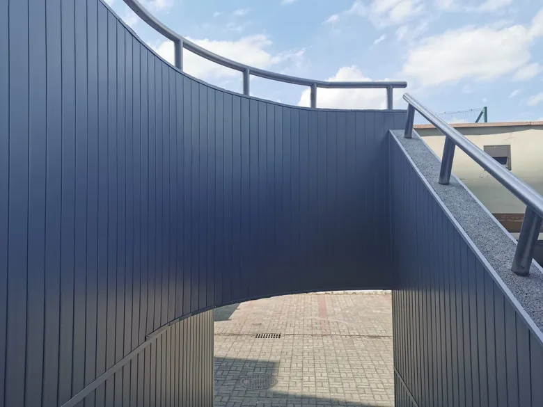 Geschwungene Fassade aus graphitfarbenen Aluminiumpaneelen