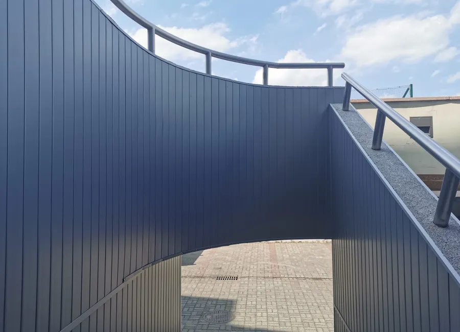 Geschwungene Fassade aus graphitfarbenen Aluminiumpaneelen