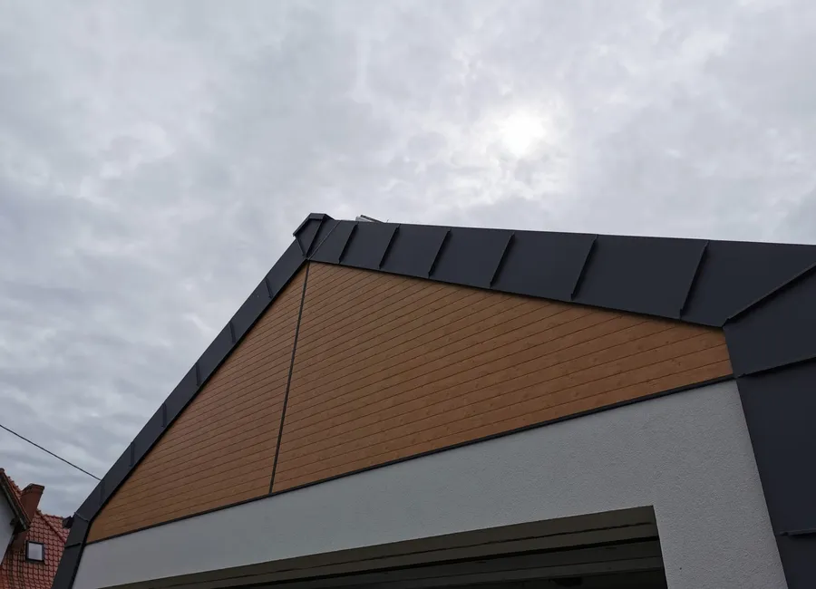 Giebel eines Gebäudes: Aluminiumpaneel im Holzdekor und Stehfalzdach
