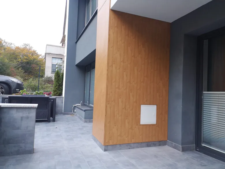 Gebäudeecke mit einem Aluminiumpaneel im Holzdekor neben der Terrasse