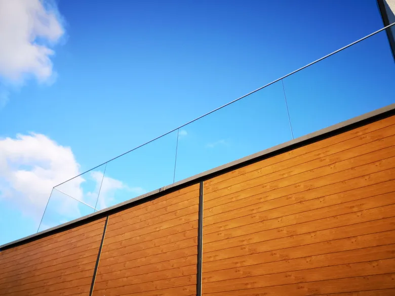 Detail einer Aluminiumfassade im Holzdekor neben einer Glasbrüstung
