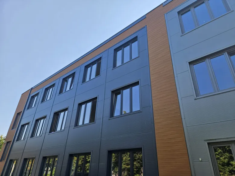 Fassade eines Bürogebäudes aus Aluminiumpaneelen: Graphit und Holzdekor