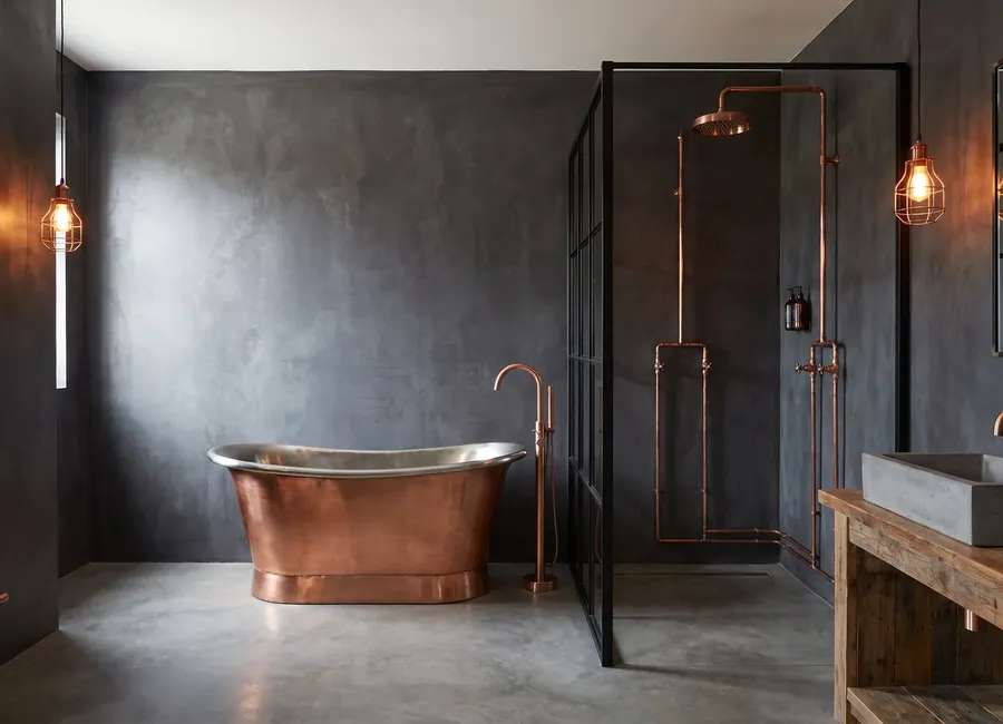 Industrial bathroom with copper: a copper bath, exposed copper shower pipes and a reclaimed wood vanity, walls in panels in the Graphite C finish